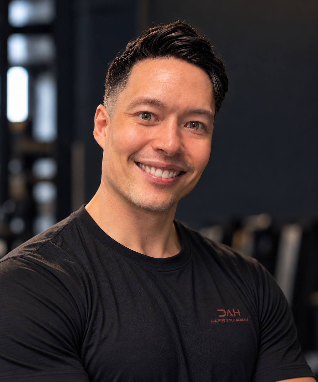 Portrait of Didrik Alexander Helle smiling in a black shirt with a red DAH Coaching and Performance logo